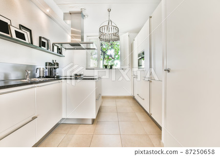 Kitchen in scandinavian style with white glossy furniture and with the necessary equipment Kitchen in scandinavian style with white glossy furniture and with the necessary equipment 87250658