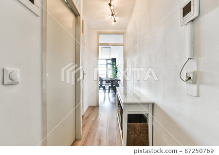 Long narrow corridors in a modern apartment with white doors 87250769