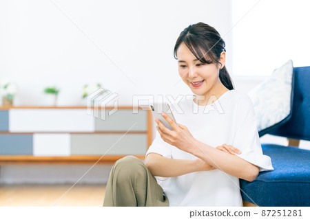 年輕女子在客廳看智慧型手機 年輕女子在客廳看智慧型手機 87251281