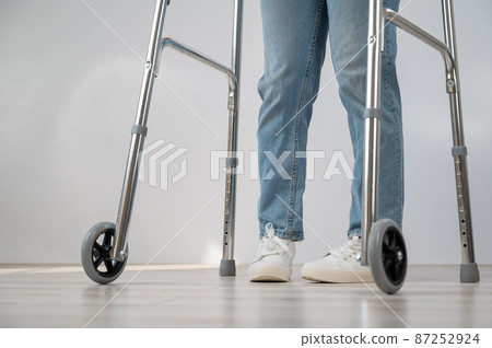 Close-up of female legs with walkers. The girl walks with the help of special equipment. 87252924