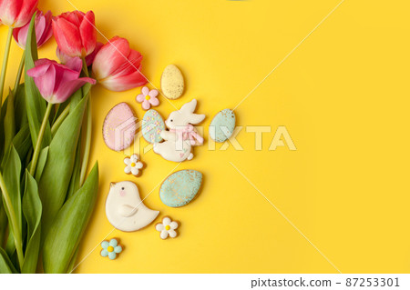Happy Easter. Multi-colored pastel easter cookies gingerbread, seasonal flowers tulips on yellow background. Easter concept, copy space, flyer, banner, coupon, greeting card, invitation Happy Easter. Multi-colored pastel easter cookies gingerbread, seasonal flowers tulips on yellow background. Easter concept, copy space, flyer, banner, coupon, greeting card, invitation 87253301