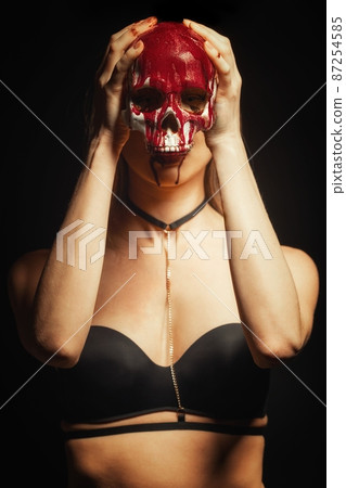 Woman holding bloody skull against dark background Woman holding bloody skull against dark background 87254585