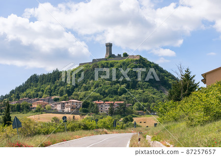 Radicofani town beneath and Fortress (Fortezza di Radicofani) on a basaltic cliff. Tuscany, Italy 87257657