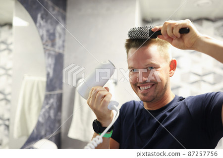 Happy man doing his own blow-drying at home 87257756