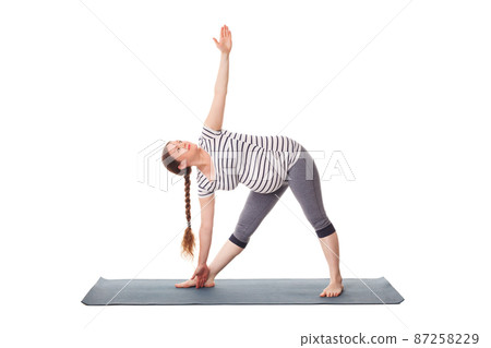 Pregnant woman doing yoga asana Utthita trikonasana 87258229