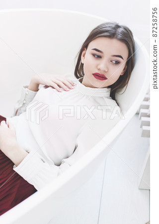 Portrait of fashionable women in red skirt and white blouse posing in a bath Portrait of fashionable women in red skirt and white blouse posing in a bath 87258756