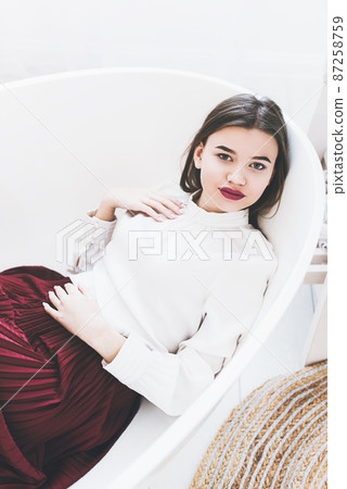 Portrait of fashionable women in red skirt and white blouse posing in a bath Portrait of fashionable women in red skirt and white blouse posing in a bath 87258759