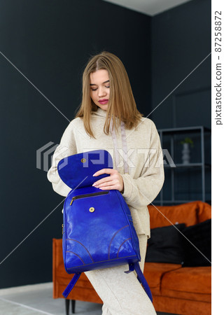 photo of a women in beige sports suit and blue leather backpack posing in a hotel room. selective focus photo of a women in beige sports suit and blue leather backpack posing in a hotel room. selective focus 87258872
