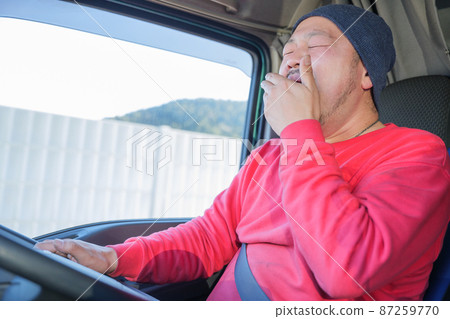Male driver yawning and driving a heavy truck 87259770
