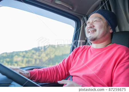 A smiling male driver driving a heavy truck 87259875