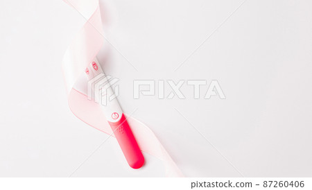 Pregnancy test isolated. Positive woman pregnant test with pink silk ribbon on white background. Medical healthcare gynecological, pregnancy fertility maternity people concept. Pregnancy test isolated. Positive woman pregnant test with pink silk ribbon on white background. Medical healthcare gynecological, pregnancy fertility maternity people concept. 87260406