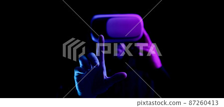 Vr goggles virtual reality. Young man in digital helmet for 3d virtual reality game isolated on black neon background. Study and virtual world in 3D simulation. 87260413