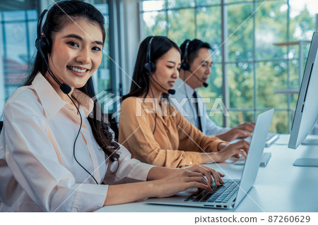Business people wearing headset working actively in office Business people wearing headset working actively in office 87260629
