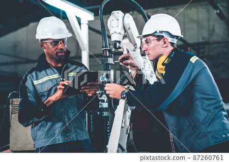 Factory workers working with adept robotic arm in a workshop 87260761