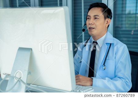 Doctor wearing headset talking actively on video call in a clinic or hospital . 87260789