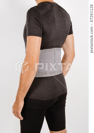 Lumbar brace on the human body isolated on a white background. Trauma of back. Back brace, orthopedic lumbar, support belt for back muscles. Lower back problems health. 87261126