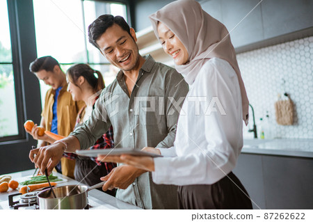 friend cooking together in the kitchen while looking at online course from tablet pc 87262622
