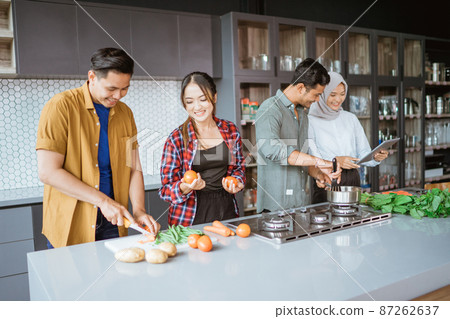 friend cooking together in the kitchen while looking at online course from tablet pc 87262637