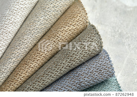 Fabric swatches in different colors are stacked for selection. A variety of shades of upholstery material for furniture and interior. Fabric texture close up. A set of multi-colored rolls of material Fabric swatches in different colors are stacked for selection. A variety of shades of upholstery material for furniture and interior. Fabric texture close up. A set of multi-colored rolls of material 87262948
