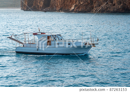 small motor yacht sails along the sea past the steep banks 87263153