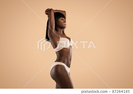 Cheerful beautiful african american woman model posing in beige underwear Cheerful beautiful african american woman model posing in beige underwear 87264185