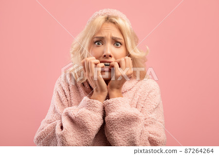 Afraid young lady biting nails with worry, having emotional stress, reacting to scary news, pink studio background Afraid young lady biting nails with worry, having emotional stress, reacting to scary news, pink studio background 87264264