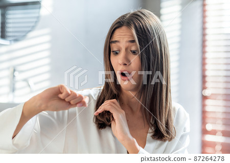 Shocked Woman Looking At Her Dry Brittle Hair While Standing In Bathroom 87264278
