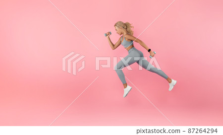 Young Woman Running With Dumbbells Isolated On Studio Background 87264294