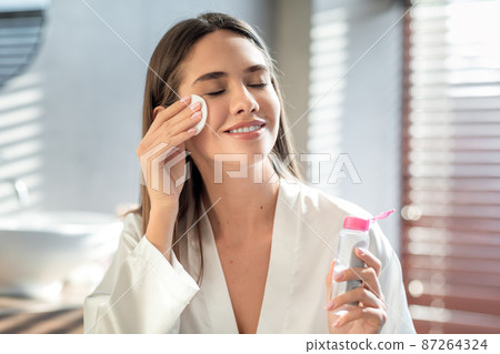 Beautiful Smiling Woman Cleansing Skin With Micellar Water And Cotton Pad 87264324