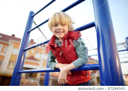 Cute preschooler boy having fun on outdoor playground. Spring summer autumn active sport leisure for kids. Activity for family with children. Equipment for entertainment park Cute preschooler boy having fun on outdoor playground. Spring summer autumn active sport leisure for kids. Activity for family with children. Equipment for entertainment park 87264343