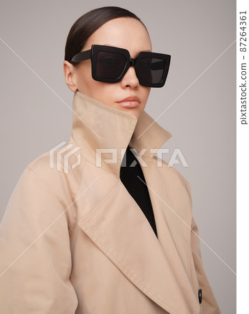 Beautiful young lady in a beige trench coat 87264361