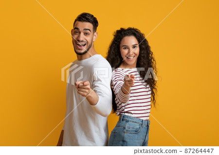 Joyful young arabic couple pointing at camera with fingers 87264447