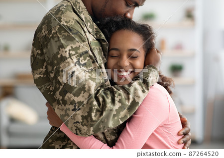 Emotional african american girl hugging her father in military uniform 87264520
