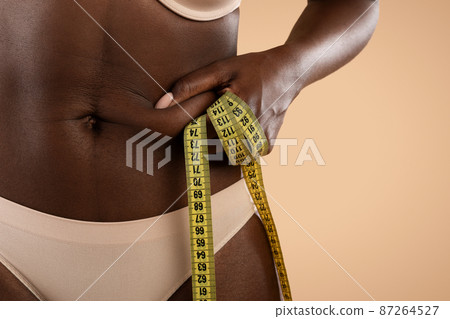Cropped of black woman in underwear pulling skin on belly Cropped of black woman in underwear pulling skin on belly 87264527