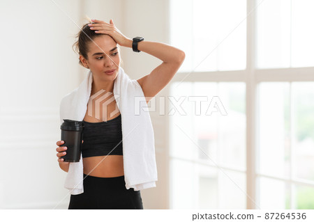 Portrait of sporty beautiful smiling woman holding shaker Portrait of sporty beautiful smiling woman holding shaker 87264536