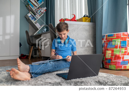 Concentrated remote student writing down in his notebook Concentrated remote student writing down in his notebook 87264933