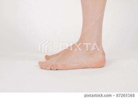 Barefoot and legs isolated on white background. Closeup shot of healthy beautiful female feet. Health and beauty concept. Side view of human foot ream with neutral manicure or pedicure. Sole of foot. 87265168