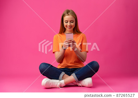 Portrait of a young woman using mobile phone over color background. 87265527