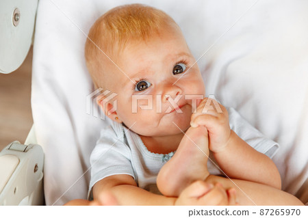 Cute little newborn girl with smiling face looking at camera on white background. Infant baby resting playing lying down on feeding chair at home. Motherhood happy child concept Cute little newborn girl with smiling face looking at camera on white background. Infant baby resting playing lying down on feeding chair at home. Motherhood happy child concept 87265970