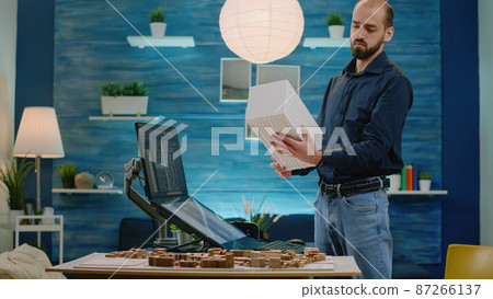 Man working as architect holding maquette and using touch screen 87266137