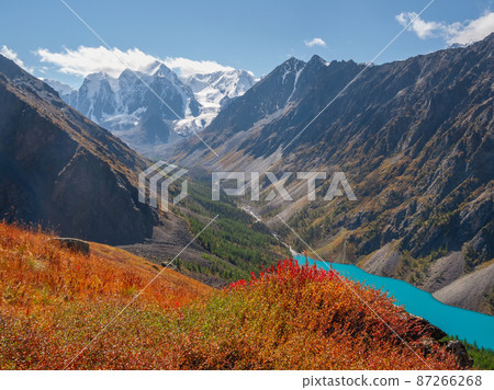 Blue mountain lake in the caldera. Mountain range against a cloudy sky. Caldera of an extinct volcano is surrounded by a mountain range. Sunny autumn yellow high-altitude plateau. 87266268