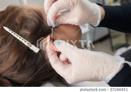 Stretched lobe piercing, grunge concept. Pierced woman ear with black plug tunnel. industrial and rook. 87266951