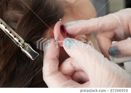 Stretched lobe piercing, grunge concept. Pierced woman ear with black plug tunnel. industrial and rook. 87266958