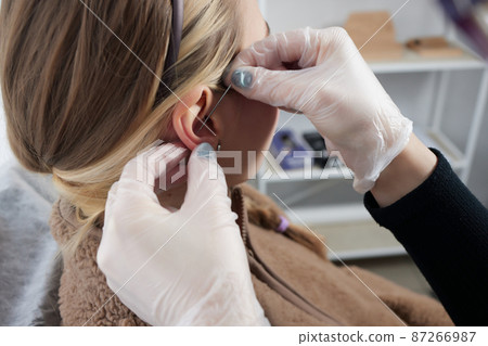 piercings on an ear. Conch and helix piercings close up. 87266987