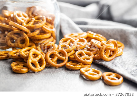 Mini pretzels. Crusty salted snack on kitchen table. 87267038