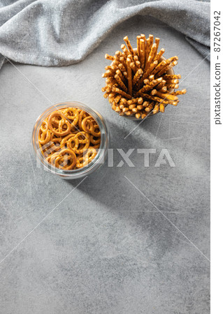 Mini pretzels and salted sticks. Crusty salted snack on kitchen table. 87267042