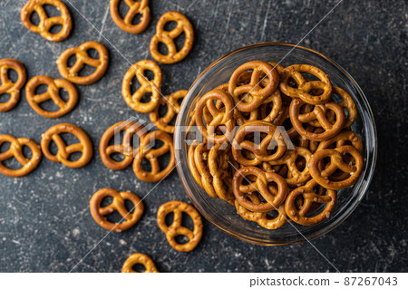 Mini pretzels. Crusty salted snack in bowl. 87267043