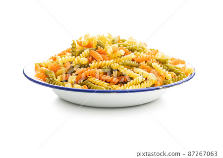 Three colors fusilli pasta in bowl. Colorful italian raw pasta isolated on white background. Three colors fusilli pasta in bowl. Colorful italian raw pasta isolated on white background. 87267063