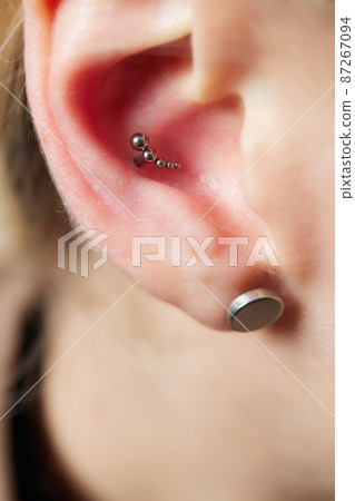 piercings on an ear. Conch and helix piercings close up. 87267094