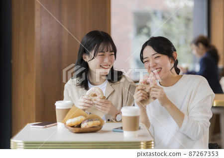 Young woman eating donuts in a cafe 87267353